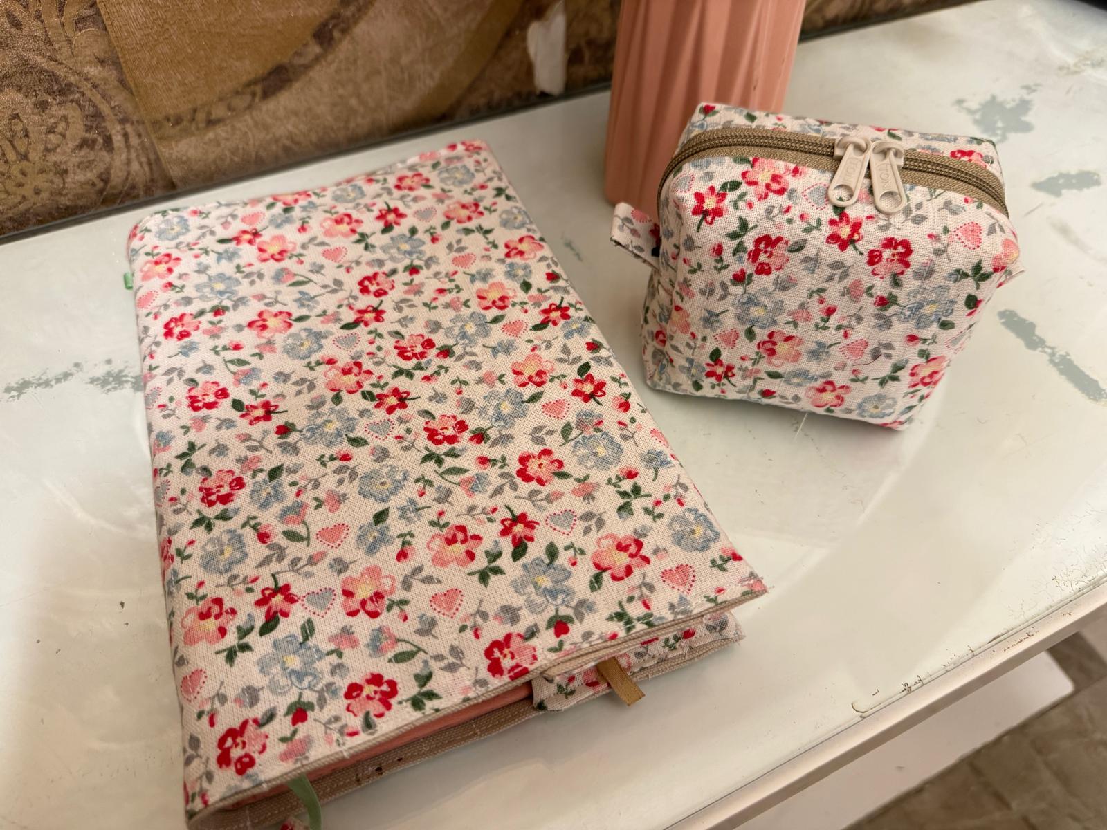A matching floral fabric book cover and zippered pouch in pink, red and blue