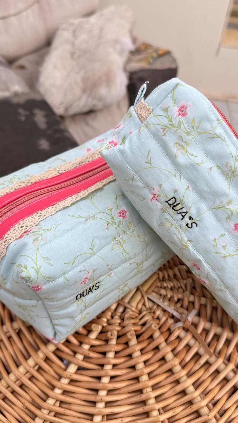 Two personalised light blue floral quilted pouches with pink zippers and lace trim